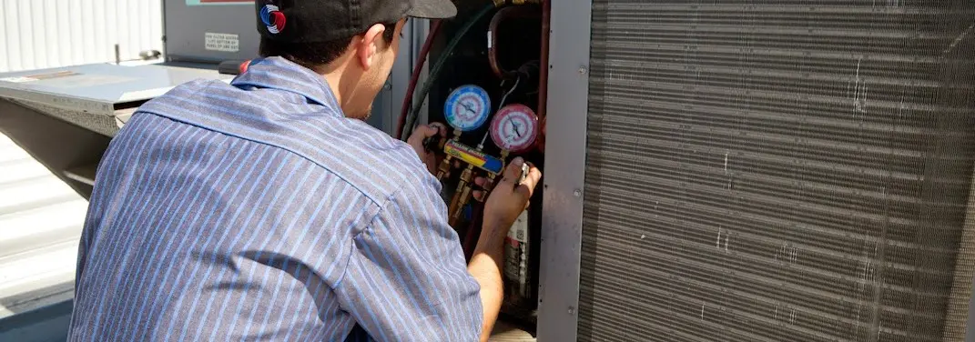 HVAC technician servicing a condenser unit in Hondo