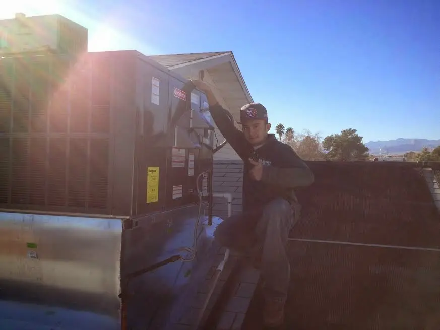 HVAC technician performing AC Tune-Up on a rooftop unit in Hondo